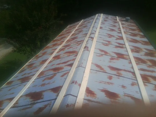 Rusted metal roof panels with new wood purlins before replacement — Storm Damage Roof Repair in Maple Grove by Roofing Brothers