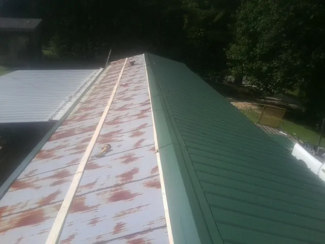 Old rusted panels beside newly installed green metal roofing — Wind Damage Roof Repair by Roofing Brothers in Maple Grove