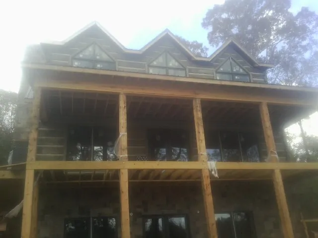 Dormers and porch framing on a large log home under construction — Roof Coating work by our crew in Maple Grove