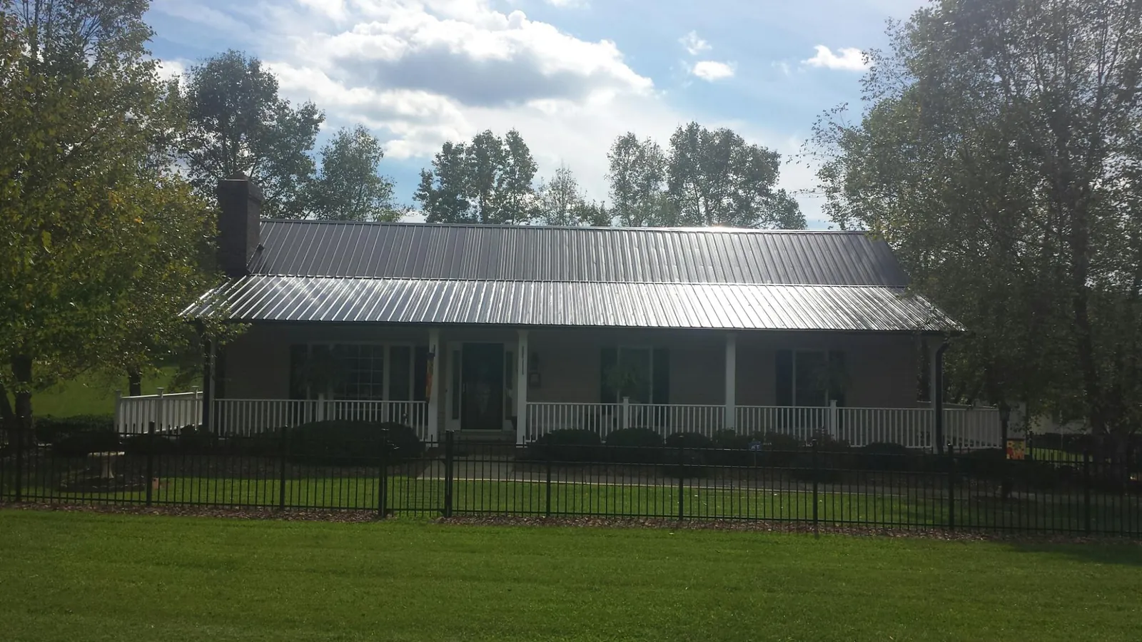 Gray metal roof on a brick ranch with a full width front porch — Gutter Guard Installation work by our crew in Maple Grove