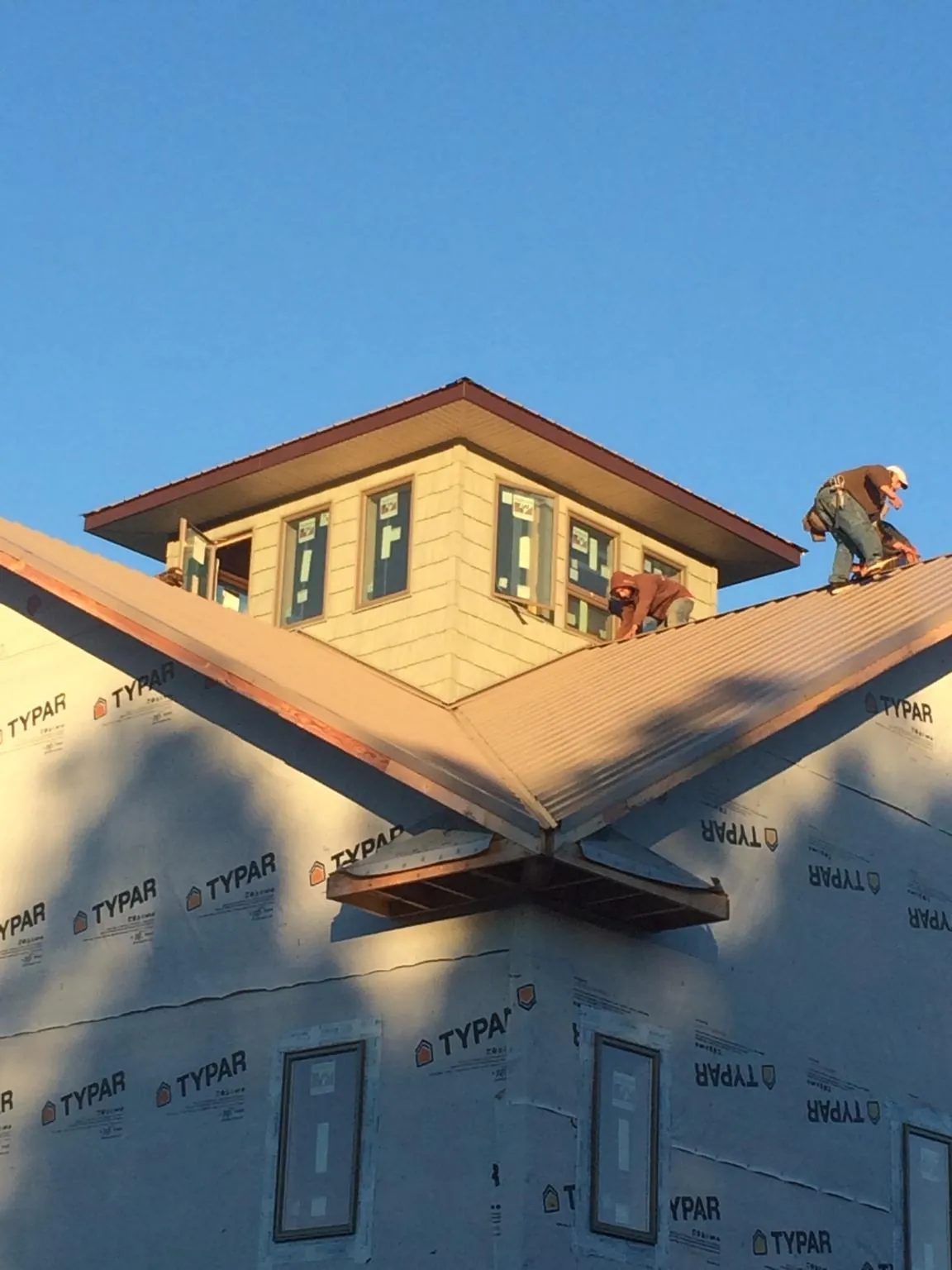 Roofers working around a rooftop cupola on a new metal roof at sunset — Roof Waterproofing in Maple Grove by Roofing Brothers